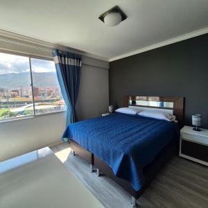 a bedroom with a blue bed and a large window at Premium Apartamentos Torre Azul in Cochabamba