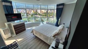 a bedroom with a bed and a large window at Premium Apartamentos Torre Azul in Cochabamba
