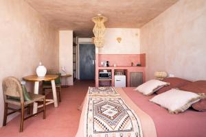 a bedroom with two beds and a table and a kitchen at Formentera Especial in La Savina
