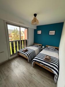 two beds in a room with a large window at Les terrasses de la Baule in La Baule