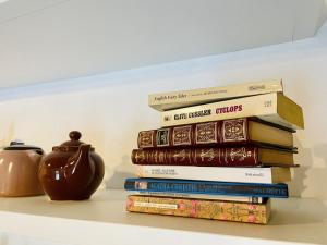 a stack of books sitting on a shelf with a vase at Casina 57 in Loro Ciuffenna