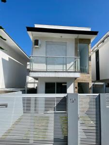 ein weißes Haus mit einem Zaun davor in der Unterkunft Casa prox. a praia do Campeche in Florianópolis