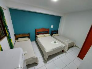 a room with two beds and a blue wall at Refugio Prumirim Green Heaven in Ubatuba