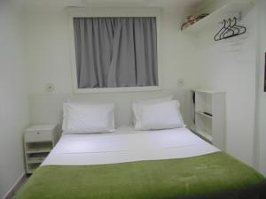 um pequeno quarto com uma cama branca e uma janela em Amarhotel em São Paulo
