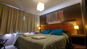 Un dormitorio con una cama grande con almohadas azules. en Belgrano Decks, en San Carlos de Bariloche