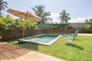 ein Schwimmbad mit einem Sonnenschirm und einem Stuhl und einem Stuhl sidx sidx in der Unterkunft OKA Milagres Cond. Beira Mar para 08 Pessoas in Barra do Camaragibe