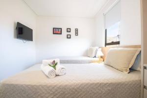 ein weißes Schlafzimmer mit zwei Handtüchern auf einem Bett in der Unterkunft OKA Milagres Cond. Beira Mar para 08 Pessoas in Barra do Camaragibe + 21 Fotos