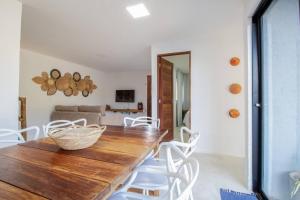 a dining room with a wooden table and white chairs at Casa Milagres 03 suítes - a 300m da Praia in Tatuamunha