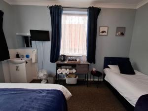 a bedroom with two beds and a window at Westbrook Lodge Guest House in Margate