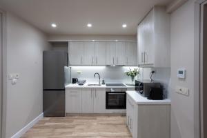 a kitchen with white cabinets and a stainless steel refrigerator at Stay Central in Ioannina