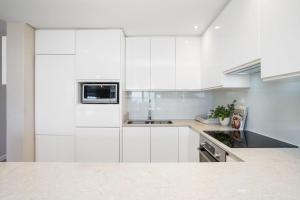 a white kitchen with white cabinets and a microwave at Dolphin Beach H106 by Host Agents in Bloubergstrand +31 photos