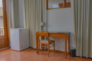 a desk with a chair and a refrigerator in a room at Hotel Continental (Cajamarca) in Cajamarca
