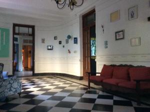ein Wohnzimmer mit einem roten Sofa und einem karierten Boden in der Unterkunft Casa Chango Hostel in Tandil