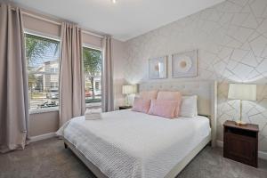 a bedroom with a white bed with pink pillows and a window at Gorgeous 6-bedroom house with private pool in Kissimmee