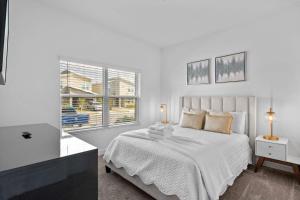 Un dormitorio blanco con una cama y una ventana. en Spacious 5BR Home with Pool Near Top Attractions, en Kissimmee