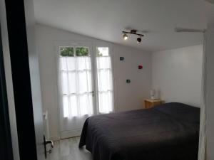 ル・ボワ・プラージュ・アン・レにあるMaison Les Tamarisのベッドと大きな窓のある寝室 +4枚の写真