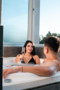 a man and a woman in a bath tub with a glass of wine at Armonium Airport in Ezeiza