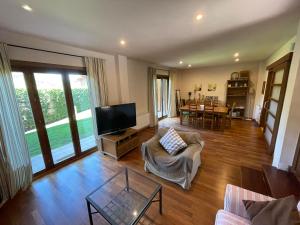 a living room with a couch and a tv and a table at House surrounded by mountain and nature in Riu de Cerdanya
