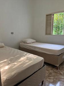 two beds in a room with a window at Sítio Veredas Formiga-MG in Formiga