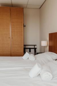 a bedroom with a bed with white sheets and towels at Studio's De Vlijt Texel in De Cocksdorp