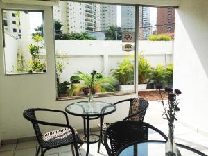 a glass table and chairs on a balcony with windows at Amarhotel in Sao Paulo