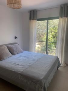 una camera da letto con un letto e una grande finestra di Maison Rez-de-jardin 80 m de la plage a Serra di Ferro