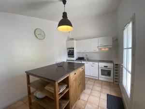 Una cocina con una mesa y un reloj en la pared. en Villa du Puits Cache, en Le Bois-Plage-en-Ré