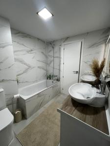 a white bathroom with a tub and a sink and a tubermott at Apartman Leoni 1 linea in Salou +40 photos