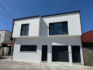 a white house with black windows at Apartamentos AbAc in Muxia