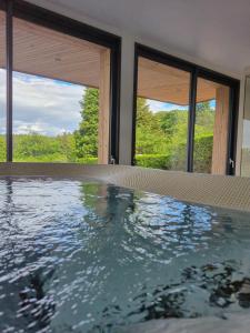 a swimming pool in a house with three windows at Aux mélèzes de Xavier GÎTE 4 étoiles in Wangenbourg