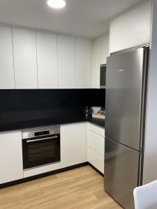 a kitchen with white cabinets and a stainless steel refrigerator at A de Lorena in Negreira
