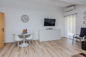 a white living room with a table and a tv at Apartmani Sanja in Vir