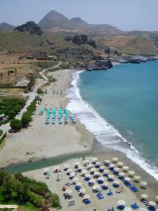 an aerial view of a beach with chairs and umbrellas at Mythos Apartments in Damnoni
