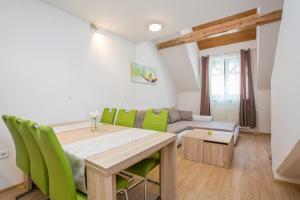 a dining room with a table and green chairs at Podkoren Apartments in Kranjska Gora