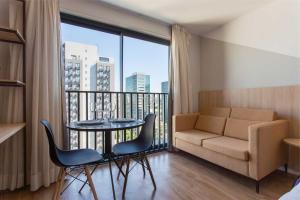 ein Wohnzimmer mit einem Tisch und einem Sofa sowie einem Balkon in der Unterkunft Moradia linda e moderna em um dos melhores bairros de Porto Alegre! in Auxiliadora