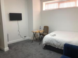Un dormitorio con una cama y una mesa con televisión. en Marina Regency, en Moffat