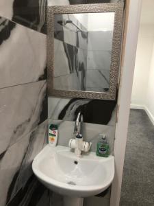 Un lavabo blanco en un baño con espejo. en Marina Regency, en Moffat