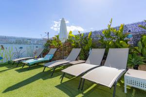 a row of lawn chairs and an umbrella at Bambus House Green in Quarteira