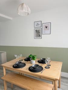 Una mesa de madera con platos y copas de vino encima. en Warner Brothers House, en Watford