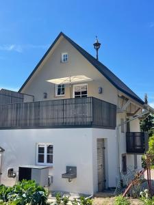 a white house with a balcony and an umbrella at Ferienhaus Pflugwirts in Oberkirch