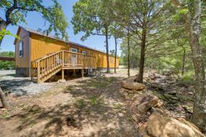 a cabin in the woods with a deck and trees at Hike, Fish and Explore Cabin Near Eufala Lake! in Crowder