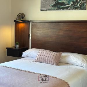 a bedroom with a bed with a wooden headboard at Hotel Le Petit in Concepción