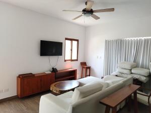 a living room with a couch and a flat screen tv at Descanso en Tortugas, Villas La Mar Monterrico in El Garitón