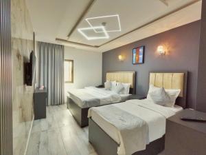 una camera d'albergo con due letti e una televisione di Holiday Season Hotel ad Aqaba