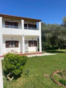 a large white house with a green yard at Elvira Apartments in Roda