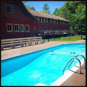 a large blue swimming pool in front of a red building at The Upper Pass Lodge in Londonderry
