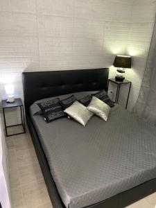 a bed with three pillows on it with two tables at GillyLoft in La Maddalena