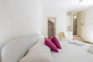 a bedroom with a white bed with purple pillows at Appartamento Liolà in Scicli