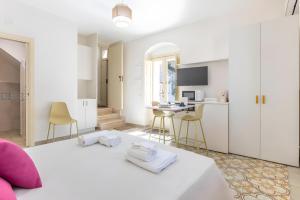 a white bedroom with a bed and a kitchen at Appartamento Liolà in Scicli
