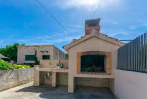 a pizza oven with a fireplace in a backyard at Apartment Ljerka in Postira